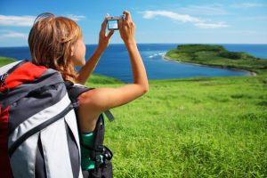 Young woman with backpack taking photo of a great landscape